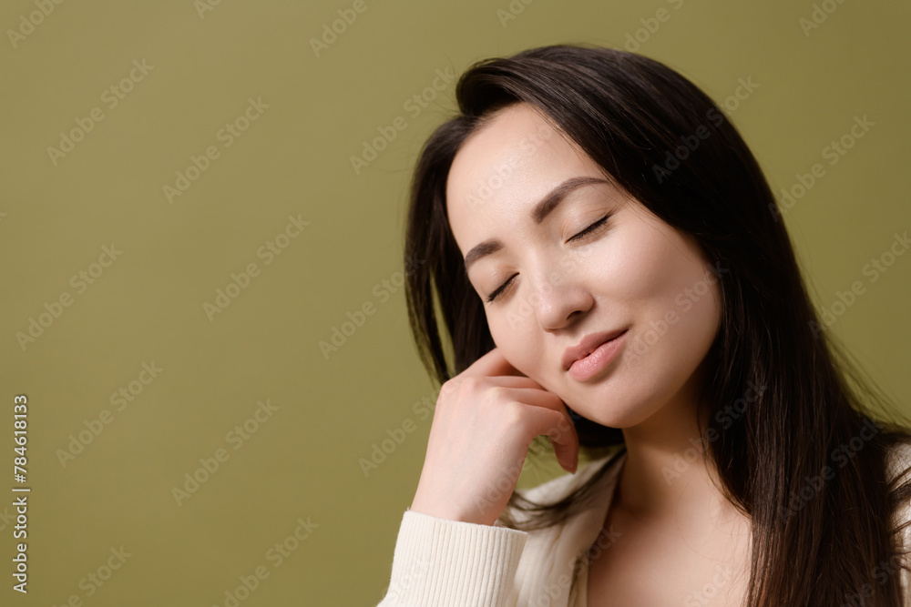 Portrait of brunette asian woman with closed eyes posing isolated on green Portrait of brunette asian woman with closed eyes posing isolated on green