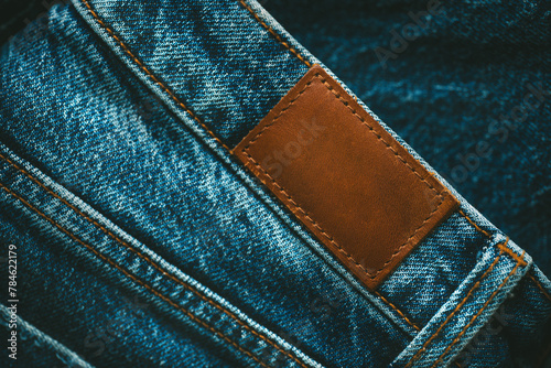 Blank brown leather empty jeans label sewed on a blue jeans denim. Style, denim and store concept.