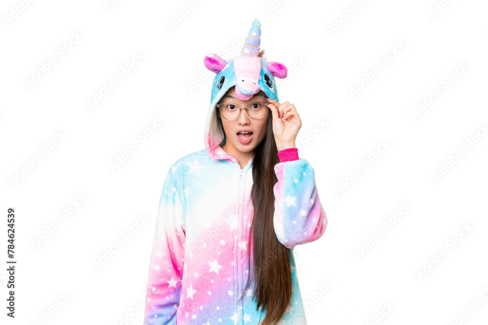 Young Asian woman with unicorn pajamas over isolated chroma key background with glasses and surprised Young Asian woman with unicorn pajamas over isolated chroma key background with glasses and surprised