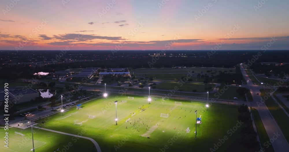 Public sports stadium with young people playing football game at sunset. Active way of life concept Public sports stadium with young people playing football game at sunset. Active way of life concept