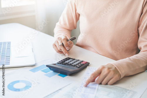 Deduction planning, debt asian young woman hand using calculator to calculating money balance from bill and income, cost budget expenses for pay money form personal individual on table at home.