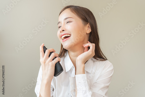 Perfume of essential aroma, beauty fashion concept. attractive perfect asian young woman hand holding perfume bottle, using spray and applying fragrance, scent at neck on body, isolated on background.