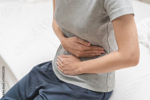 Flatulence ulcer, asian young woman, girl hands in belly, stomach pain from food poisoning, abdominal pain and digestive problem, gastritis or diarrhea. Abdomen inflammation, menstrual period people. © KMPZZZ