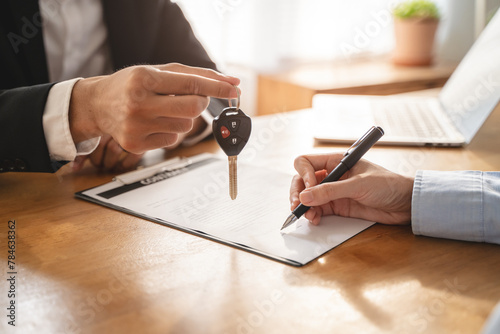 Business car rental company service, Close up hand of agent dealer giving, holding car key to customer renter, new owner after signed rental, purchase contract in document, vehicle sales agreement. photo