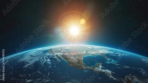 The sun is rising over the Earth  casting a warm glow over the planet. The North and South American continents are visible  as well as the Atlantic and Pacific Oceans.