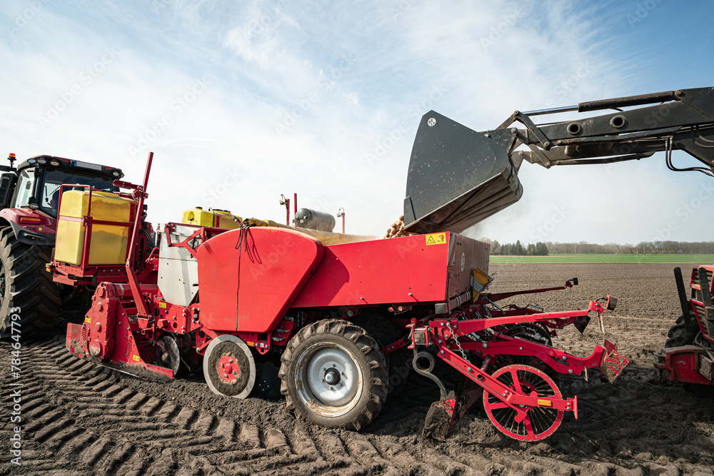 Obraz premium Anbau von Kartoffeln - Befüllen des Vorratsbunkers der Legemaschine.