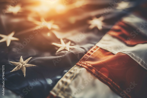 Close up of an American flag, illuminated by sunlight, blurred background. Shallow depth of field