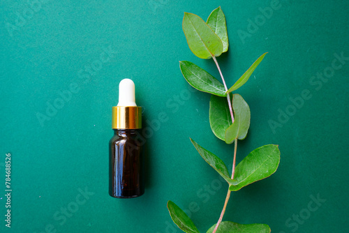 Natural cosmetics concept, dark glass vial over green background