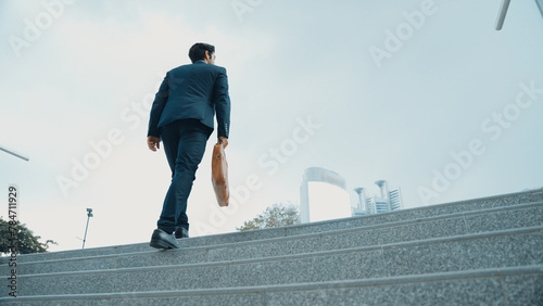 Top view of smart business man walking up stairs with bag in the hand. Professional project manager climb up the stair and going to workplace. Increasing skill, getting promotion, traveling. Exultant. photo