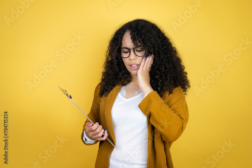 African american business woman with paperwork in hands over yellow background touching mouth with hand with painful expression because of toothache or dental illness on teeth