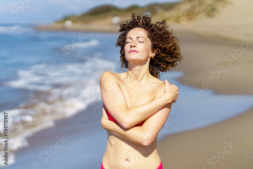 Young woman standing on sandy beach on sunny day