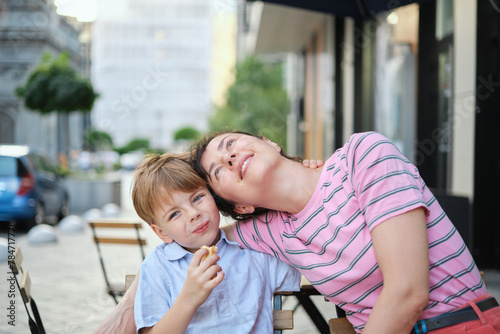 Wallpaper Mural Young mother and her son having sweets in outdoor restaurant on summer day. Sitting together, hugging and laughing, enjoying weekend. High quality photo Torontodigital.ca