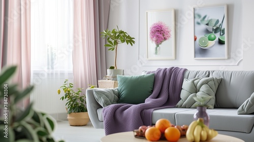 Grey settee with green cushions and purple blanket, white living room interior with coffee table with fruits photo