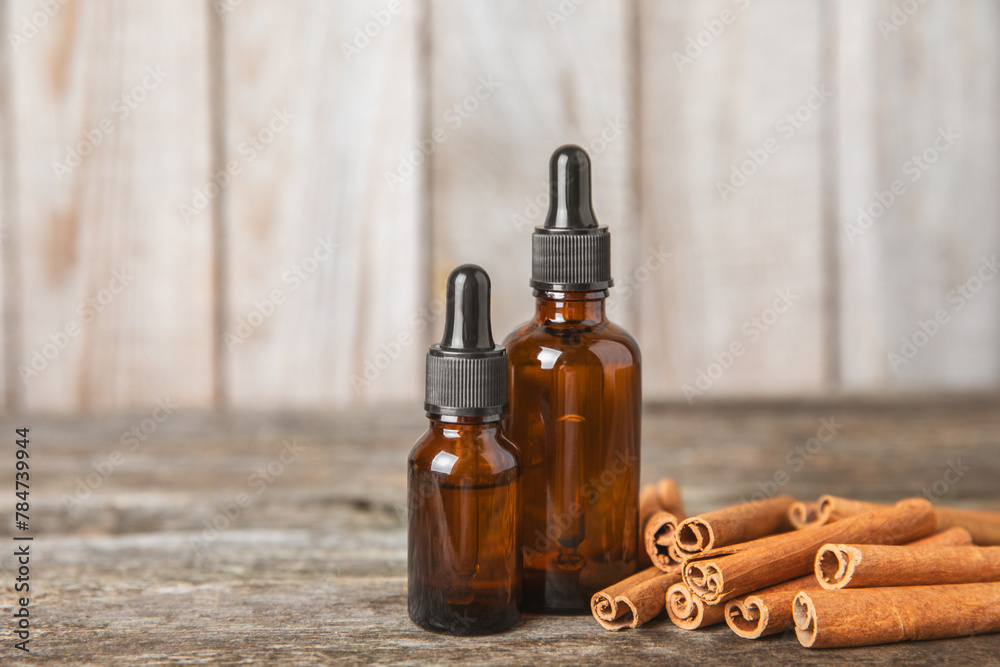 Cinnamon aromatic essential oil and cinnamon sticks on a wooden background. Aromatherapy. Organic cosmetic oil. Spa concept. Place for text. Copy space. Cinnamon aromatic essential oil and cinnamon sticks on a wooden background. Aromatherapy. Organic cosmetic oil. Spa concept. Place for text. Copy space.