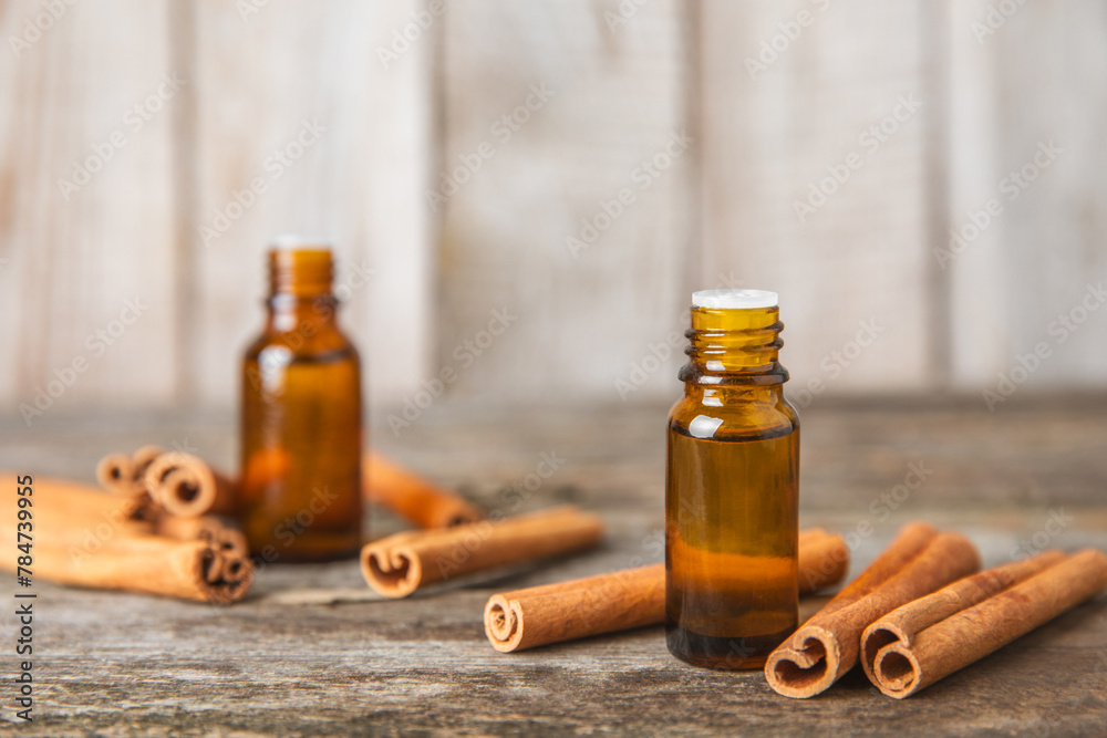 Cinnamon aromatic essential oil and cinnamon sticks on a wooden background. Aromatherapy. Organic cosmetic oil. Spa concept. Place for text. Copy space. Cinnamon aromatic essential oil and cinnamon sticks on a wooden background. Aromatherapy. Organic cosmetic oil. Spa concept. Place for text. Copy space.