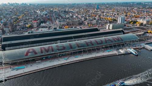 Aerial drone view Amsterdam Central Train Station with Amsterdam sign on roof. Bird's eye view autumn cityscape