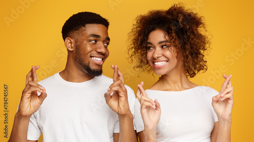 Cute black man and woman with crossed fingers making wish photo