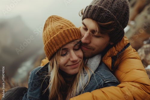 A loving couple cuddles in warm clothes with a mountainous backdrop, sharing a tender moment of affection photo