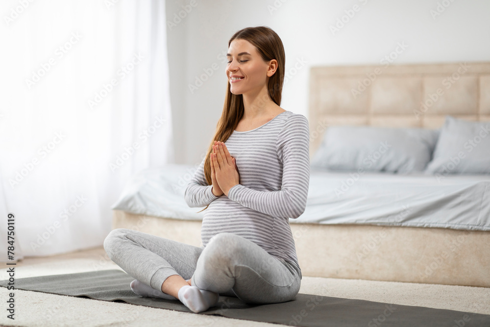 Pregnant woman practicing yoga at home, meditating Pregnant woman practicing yoga at home, meditating