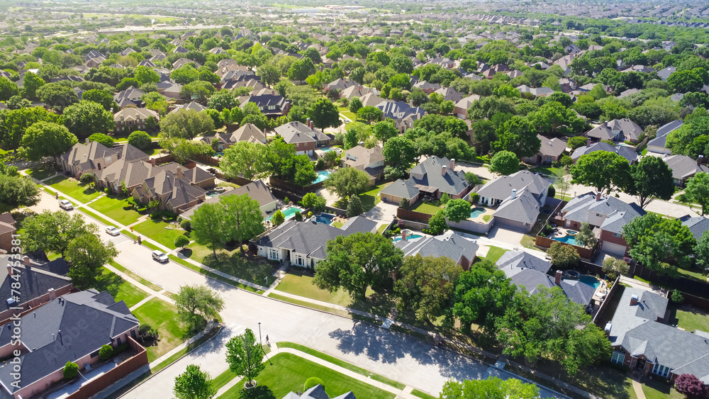 Aerial view lush greenery suburban residential neighborhood subdivision, row of upscale two-story houses with swimming pool, shingle roofing, large fenced backyard, well-trimmed HOA landscape