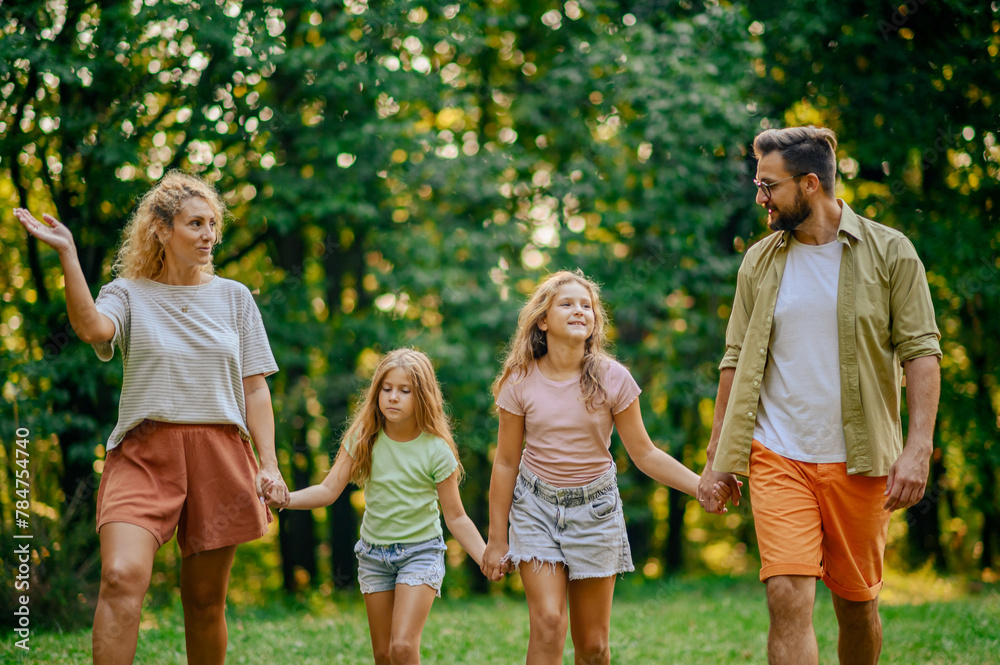 Fototapeta premium Portrait a happy family taking a walk on meadow near forest in nature.