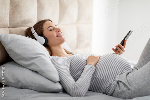 Pregnant woman using phone while relaxing at home photo