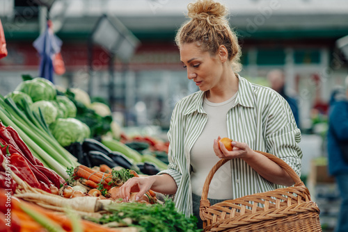 Customer choosing fresh vegetables at farmers market. photo