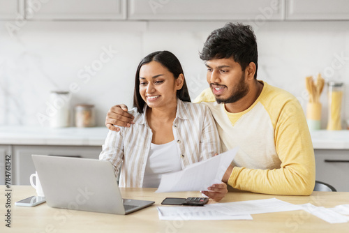 Couple engaging with finances on laptop at kicthen