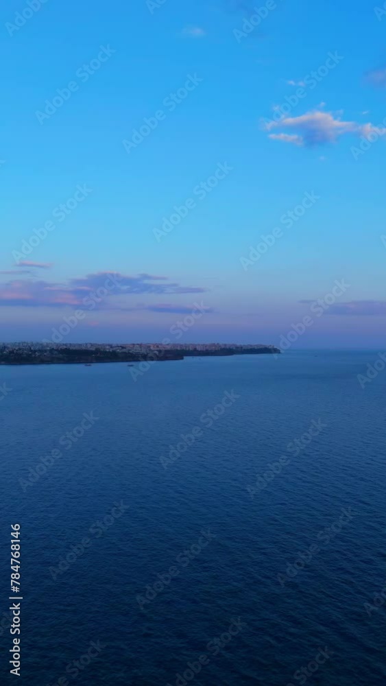 Beachfront Sunset on City Coastline: Skyline Silhouetted by Mountains