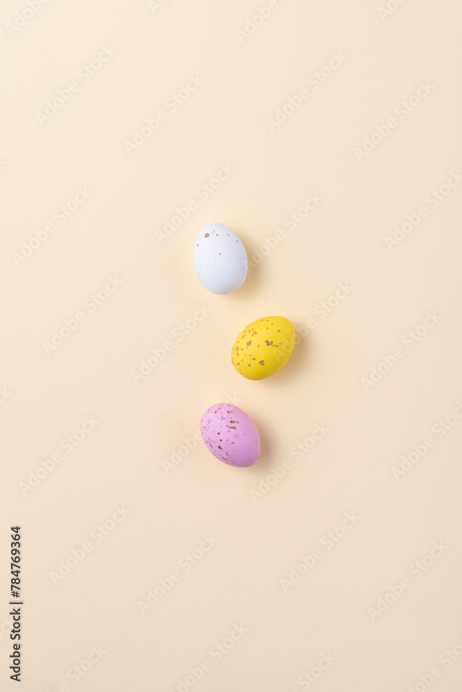 Chocolate colored Easter eggs speckled on a beige background. Minimalism Easter concept, copy space