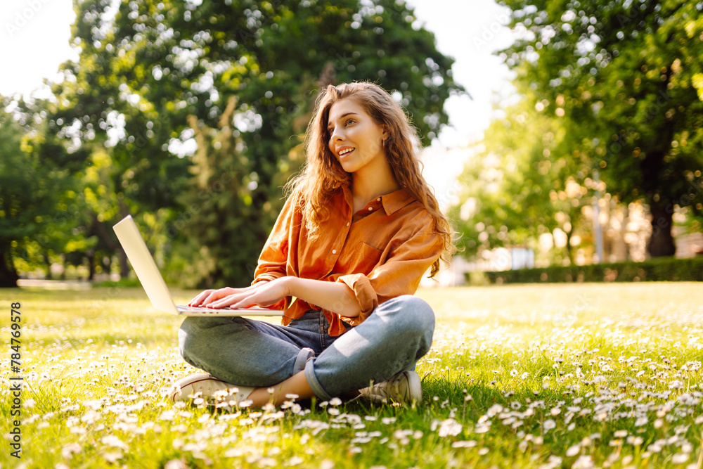 Happy woman with curly hair with a laptop outdoor. Online education, Freelance work, technology concept. Happy woman with curly hair with a laptop outdoor. Online education, Freelance work, technology concept.