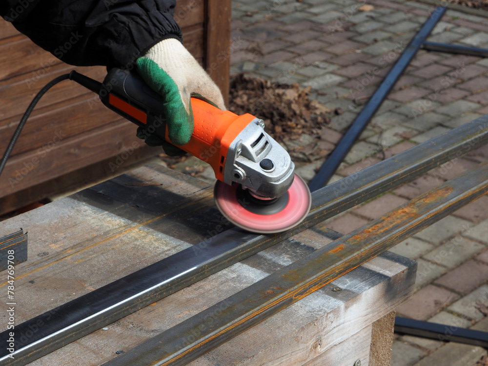 A worker processes metal with an angle grinder on a construction site.
The concept of locksmith work, processing of metal products.