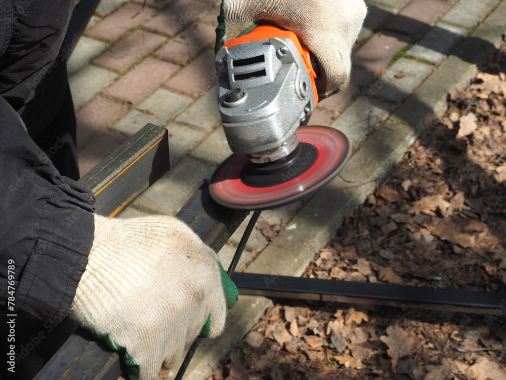 A worker processes metal with an angle grinder on a construction site.
The concept of locksmith work, processing of metal products.