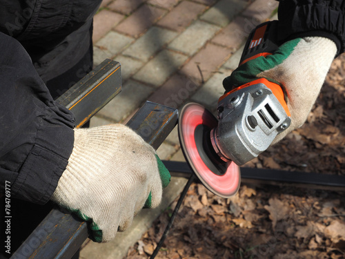 A worker processes metal with an angle grinder on a construction site.
The concept of locksmith work, processing of metal products.
