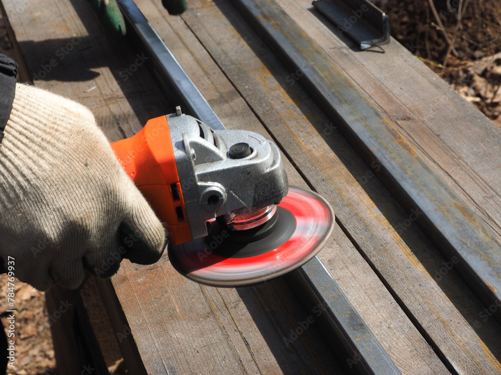 A worker processes metal with an angle grinder on a construction site.
The concept of locksmith work, processing of metal products.