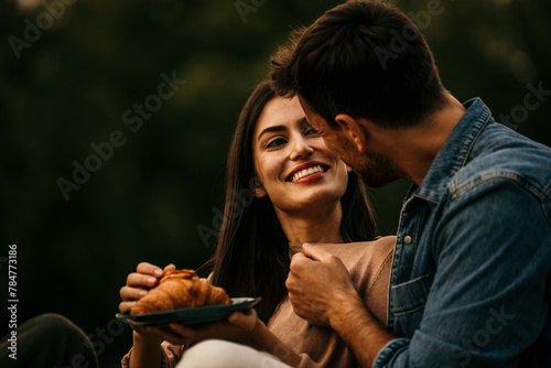 Diverse couple laughing and enjoying snacks and fresh juice during a picnic outing © La Famiglia