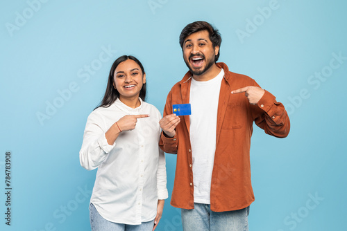 Happy couple showing a credit card on blue background