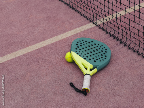 Padel Racket and Yellow Ball on a Pink Court Grass Turf Next to Net