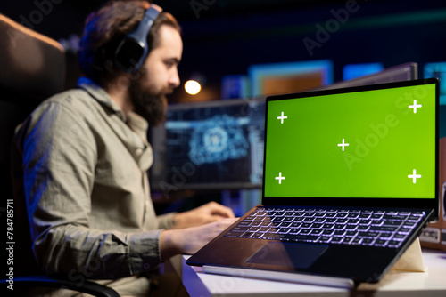 Focus on isolated screen laptop used by engineer updating artificial intelligence machine learning algorithm. Close up shot of chroma key notebook used by IT expert in blurry background programming AI