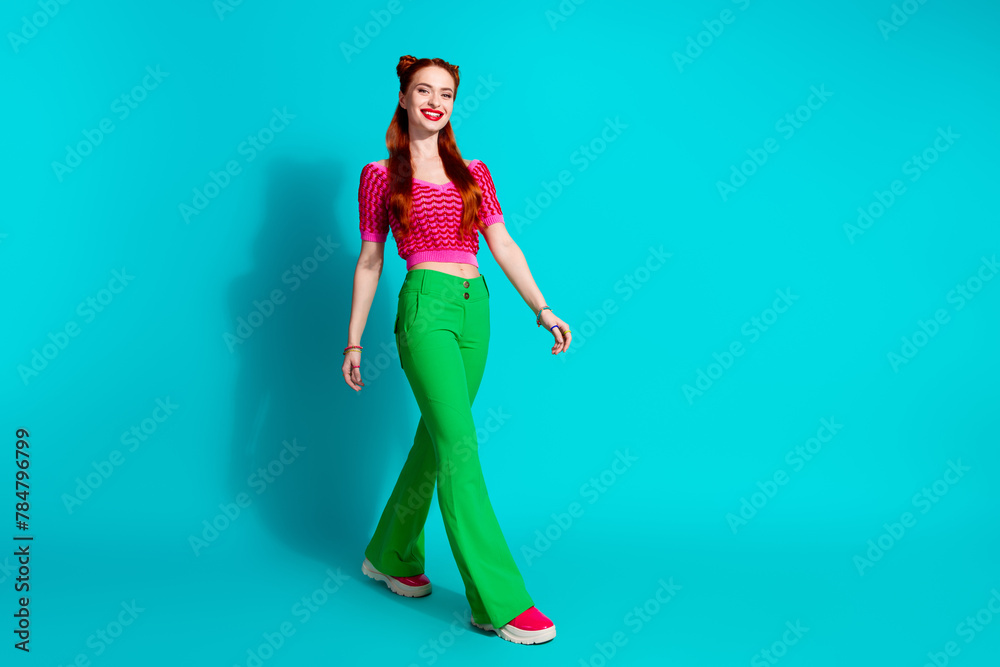 Full length photo of adorable pretty lady dressed pink knitted shirt walking emtpy space isolated blue color background - obrazy, fototapety, plakaty 