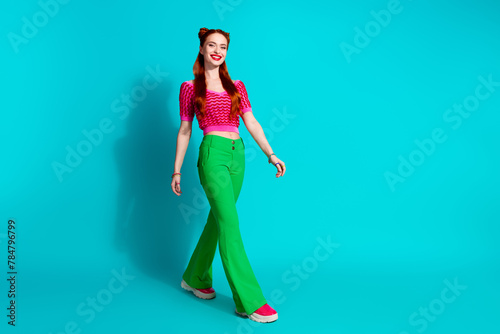 Full length photo of adorable pretty lady dressed pink knitted shirt walking emtpy space isolated blue color background