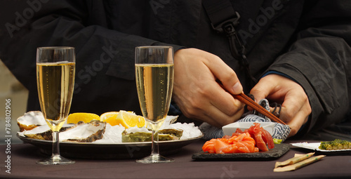 Midsection body of the man eating oysters and sushi with chopsticks at the farmers street food market in Prague.