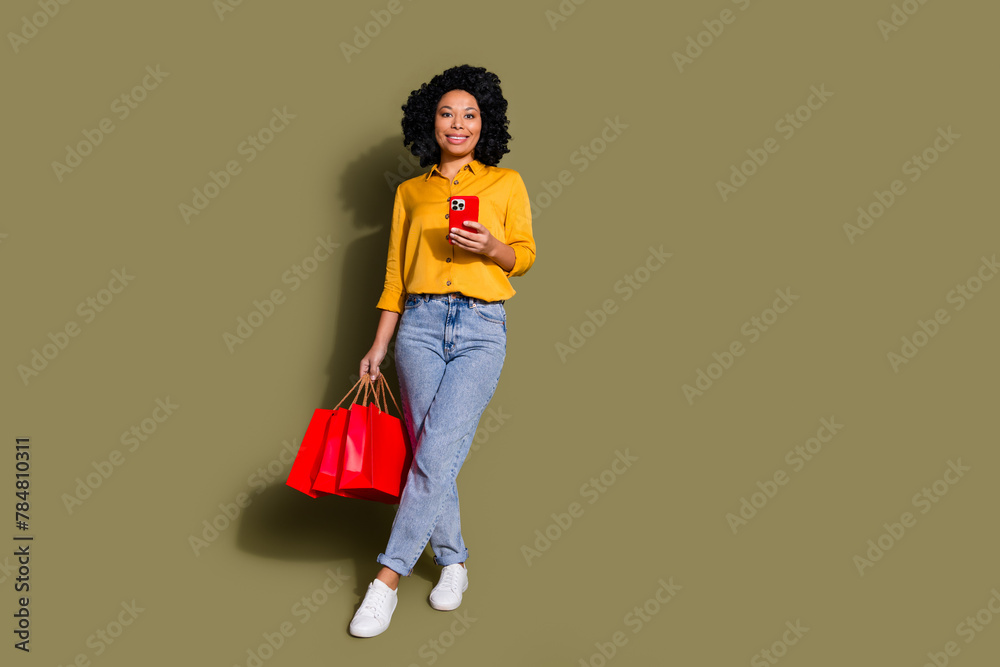 Full length portrait of pretty lady shop bags phone empty space wear yellow shirt isolated on khaki color background Full length portrait of pretty lady shop bags phone empty space wear yellow shirt isolated on khaki color background