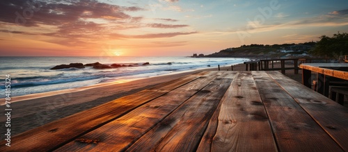 View of an old wooden seafront table, on a beach landscape with sunset photo