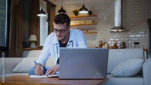 Professional young male doctor with glasses wear white uniform with stethoscope having online conference video call with patient through into laptop webcam. Remote medical counselling	