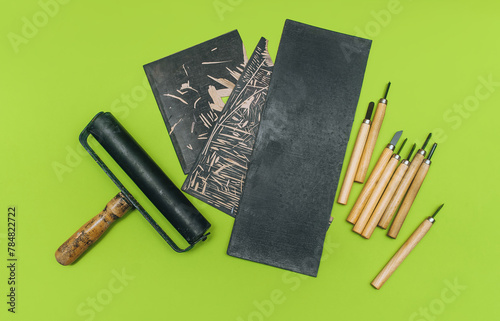 Linocut tools. Cutters, roller, black linoleum on a green background. Handicraft and design concept. Handmade creativity.