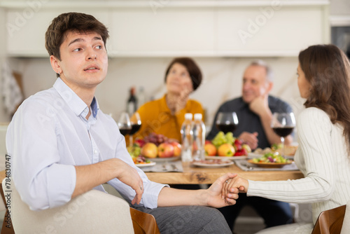 Upset young guy at family holiday table with parents at home. Unpleasant discussion