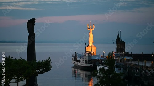 Die golden schimmernde Imperia-Statue wacht in der Morgendämmerung über dem Hafen und den See bei Vogelgezwitscher. Konstanz, Bodensee, Baden-Württemberg, Deutschland, Europa.