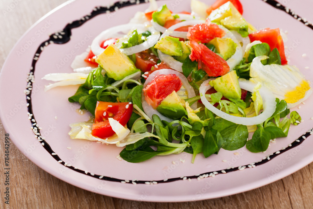 Close up of tasty salad of avocado, grapefruit, tomatoes and corn salad