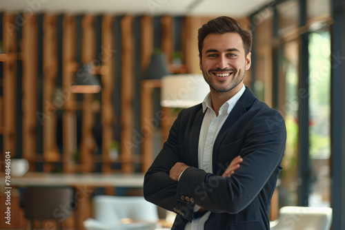 hombre joven de 30 años con traje oscuro y camisa, brazos cruzados, sobre fondo de estudio o despacho moderno con paneles de madera y decoraciones metalicas.